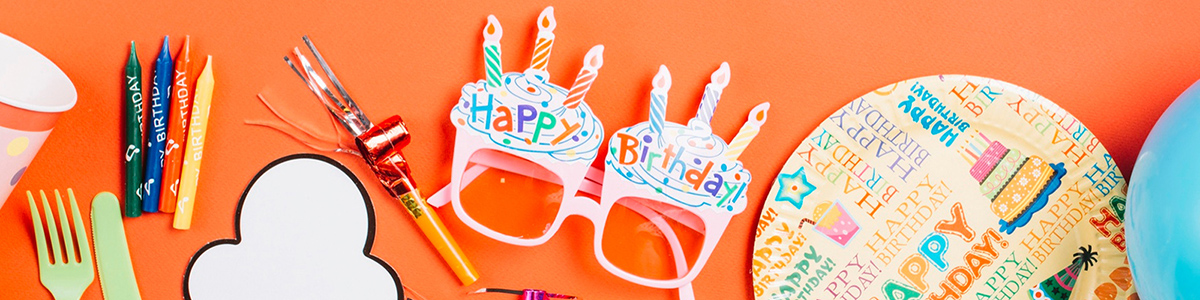 Brightly colored and polka dotted party supplies on a bright orange background